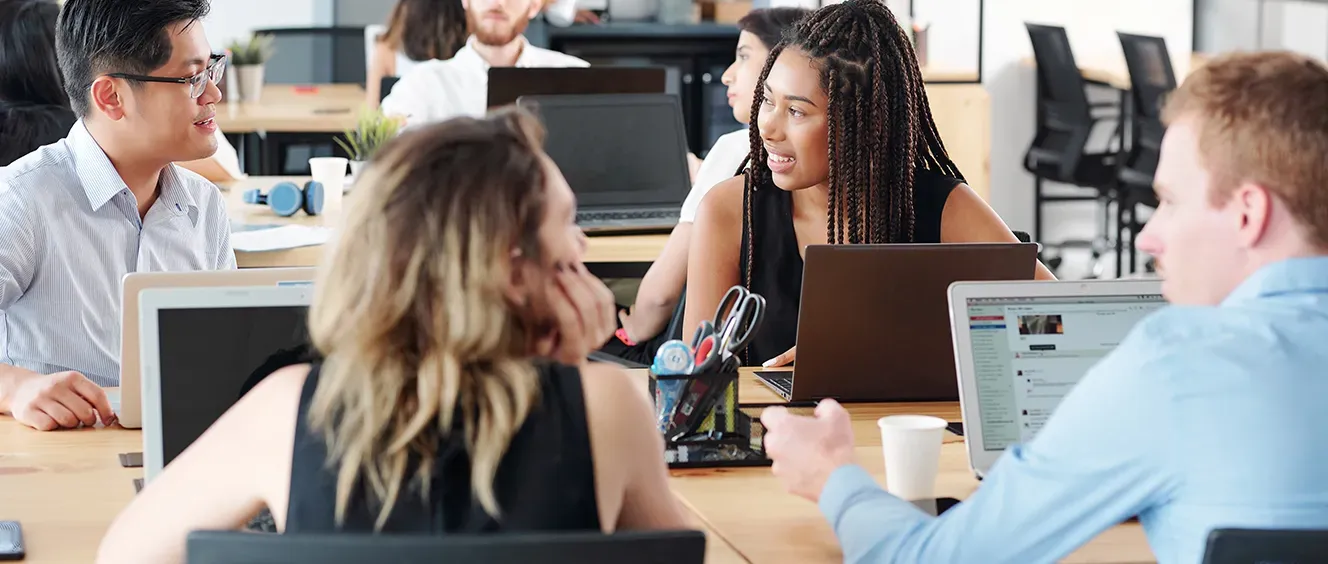 Four people looking at each other with laptops in front of them