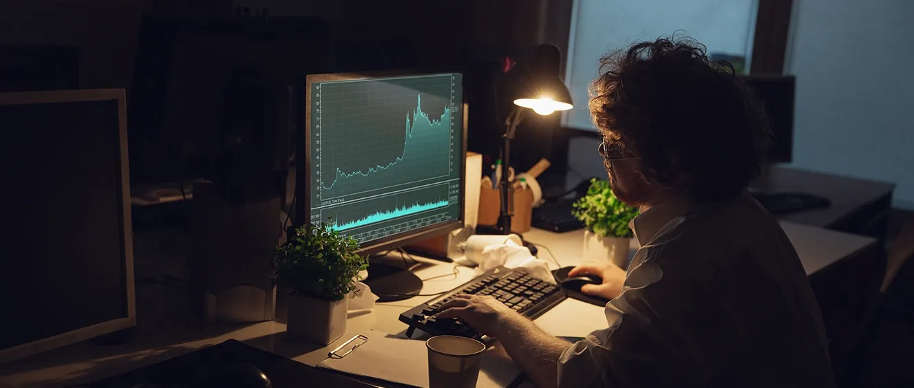 Man looking at a computer monitor in a dark office