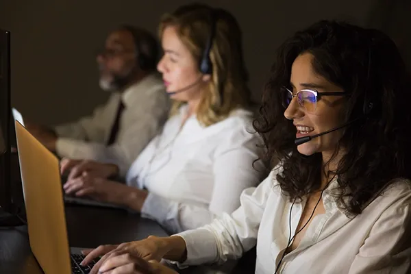 Three people with headsets on looking at screens