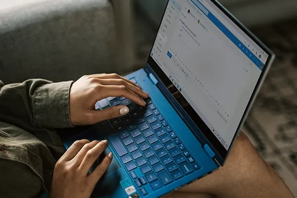 Person with a laptop on their knees typing